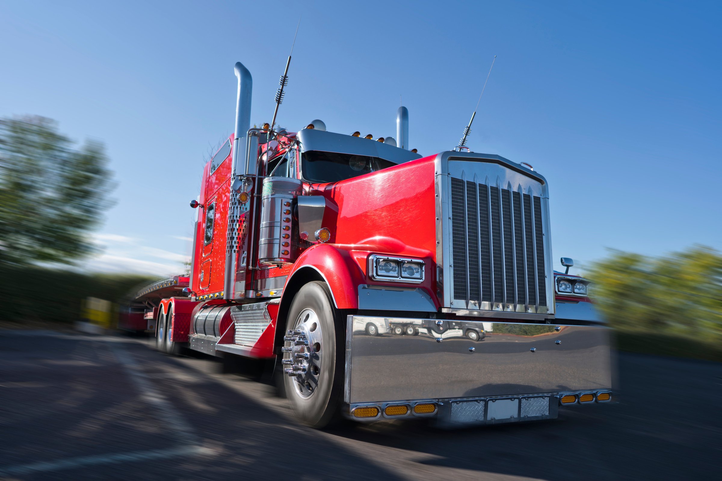 Red classic big rig semi truck with lot of chrome accessories with flat bed semi trailer stand on truck stop